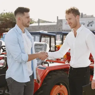 Two men shaking hands at an agricultural dealership