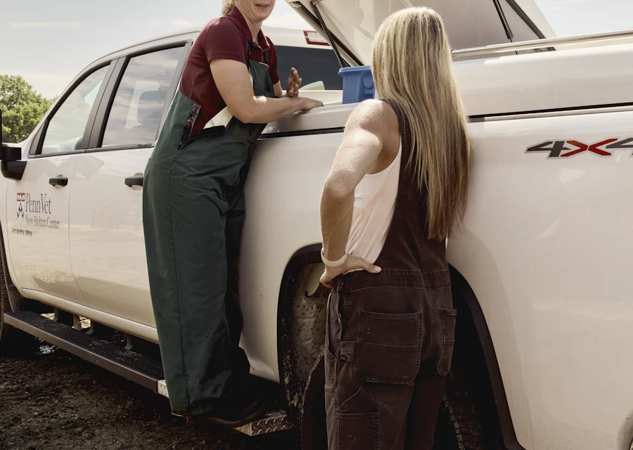 A dairy farmer and a veterinarian beside a vet truck